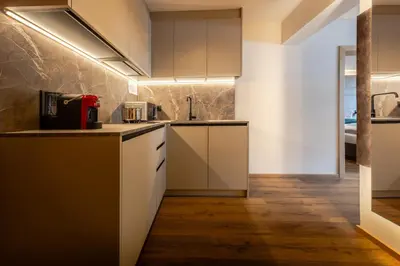 a kitchen with white cabinets and wood floors at Apartments Ursus in San Cassiano