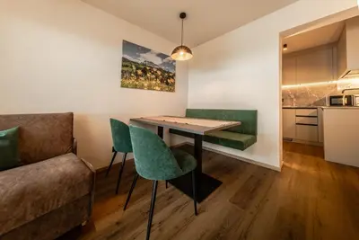 a living room with a table and green chairs at Apartments Ursus in San Cassiano