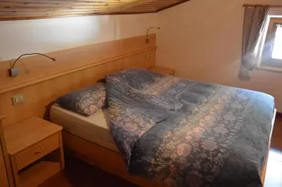 a bedroom with a bed with a wooden headboard at Cèsa Soracrepa in Canazei