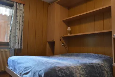 a bedroom with a bed with wooden walls and a window at Cèsa Soracrepa in Canazei