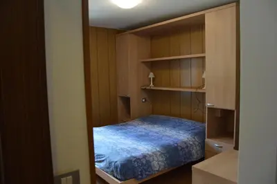 a small bedroom with a bed and shelves at Cèsa Soracrepa in Canazei
