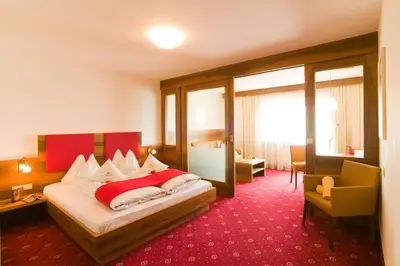 a hotel room with a bed with a red carpet at Hotel Ortler in Tirolo