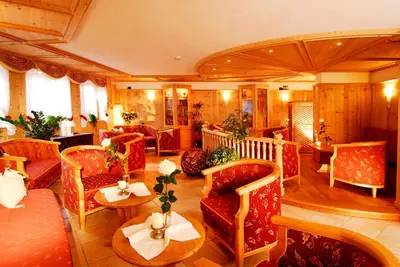a living room with red chairs and tables at Hotel Ortler in Tirolo