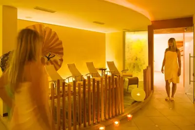 a woman walking into a room with a mirror at Hotel Ortler in Tirolo