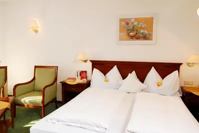 a hotel room with a bed and two chairs at Hotel Ortler in Tirolo