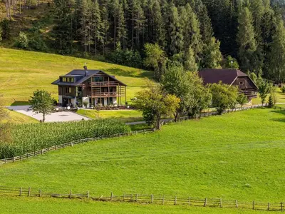 a large house in the middle of a green field at KRONPLATZ CHALET WALCHHORN - Brunico, Dolomites in Brunico
