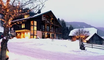 a building in the snow with lights on it at KRONPLATZ CHALET WALCHHORN - Brunico, Dolomites in Brunico