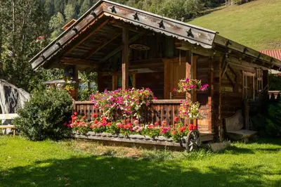 a small wooden house with flowers in the yard at Bacherhof in Val di Vizze