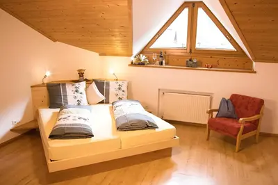 a bedroom with a bed and a window and a chair at Bacherhof in Val di Vizze