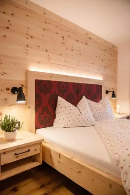 a bedroom with a large bed with a wooden wall at Alpine Chalets App. Pichlerhof in Brunico