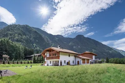 a house in a field with mountains in the background at Appartements Bäckhof in Villa Ottone