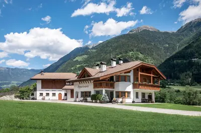 a large house with mountains in the background at Appartements Bäckhof in Villa Ottone