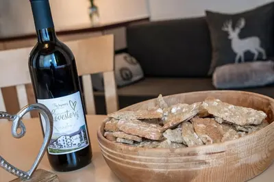 a bottle of wine next to a bowl of crackers at Appartements Bäckhof in Villa Ottone
