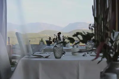 a table with a white table cloth and vases with plants at Das Panorama Designhotel in Caldaro