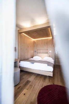a bedroom with a bed with a wooden wall at Das Panorama Designhotel in Caldaro