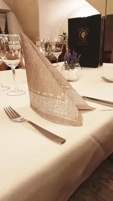 a table with a silver napkin on a table with wine glasses at Weißes Rössl in Appiano sulla Strada del Vino