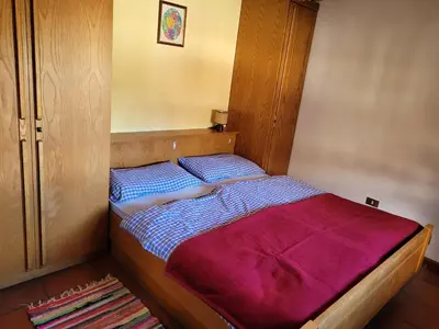 a bedroom with a bed with a red blanket at Appartements Pension Sonia in Funes