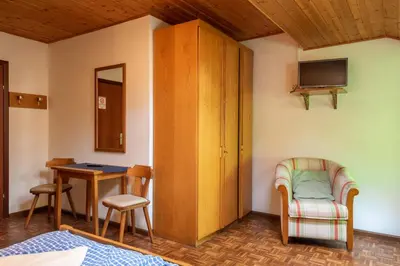 a room with a table and a chair and a cabinet at Appartements Pension Sonia in Funes