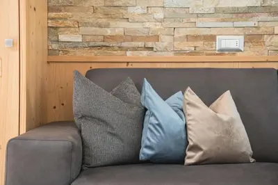 a couch with pillows on it with a brick wall at AMONIT - CLAUDIA in Selva di Val Gardena