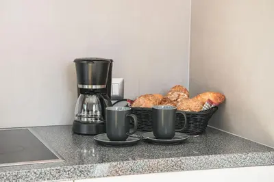 two cups of coffee and a basket of bread on a counter at AMONIT - CLAUDIA in Selva di Val Gardena