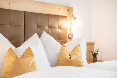 a bed with white pillows and a brown headboard at AMONIT - CLAUDIA in Selva di Val Gardena