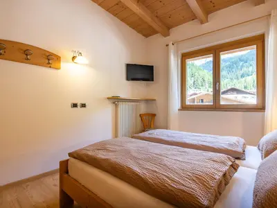 a bedroom with a bed and a couch and a window at Apartment Cesa Soraruf by Interhome in Campitello di Fassa