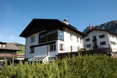 a large white house with a black roof at Artefugium Atelier in Selva di Val Gardena