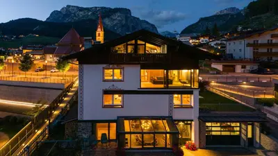 a white house with lights in a city at night at Artefugium Atelier in Selva di Val Gardena