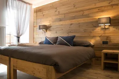 a bedroom with a wooden wall with a large bed at Agriroom in Rumo