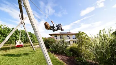 a woman is swinging on a rope swing at Weingut am Platzl in Appiano sulla Strada del Vino