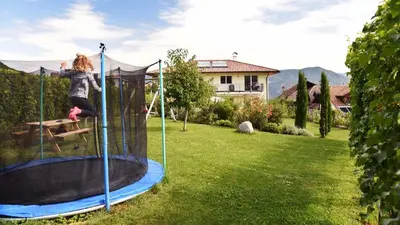 a woman jumping on a trampoline in a yard at Weingut am Platzl in Appiano sulla Strada del Vino