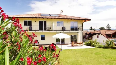 a large yellow house with a yard with flowers at Weingut am Platzl in Appiano sulla Strada del Vino