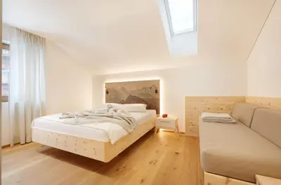 a white bedroom with a bed and a couch at Living Nature Appartements in San Vigilio Di Marebbe