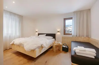 a bedroom with a bed with white sheets and a window at Living Nature Appartements in San Vigilio Di Marebbe