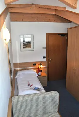 a small bedroom with a bed and a lamp at Albergo Antico in Predazzo