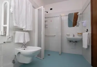 a white bathroom with a toilet and a sink at Albergo Antico in Predazzo