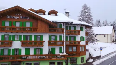 a building with green and white with snow at Albergo Antico in Predazzo