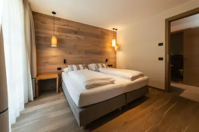 a bedroom with a large bed with a wooden wall at Lüch Da Pćëi in San Cassiano
