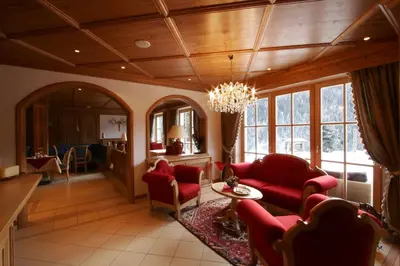 a living room with red furniture and a chandelier at Lüch Da Pćëi in San Cassiano