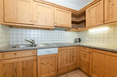 a kitchen with wooden cabinets and a sink at Lüch Da Pćëi in San Cassiano