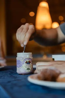 a person putting a spoon into a jar of yogurt at Lüch Da Pćëi in San Cassiano