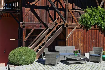 a patio with wicker chairs and a wooden staircase at Villa Lageder in Sarntal