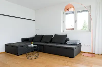 a living room with a black couch and a window at MANTANA - Apartments in San Lorenzo di Sebato