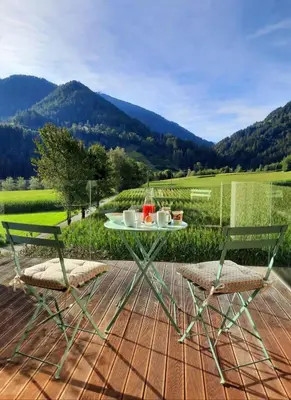 a table and chairs on a patio with mountains in the background at MANTANA - Apartments in San Lorenzo di Sebato