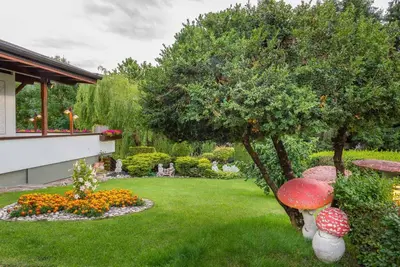 a garden with a green yard with a tree and flowers at Hotel Latemar in Castello di Fiemme
