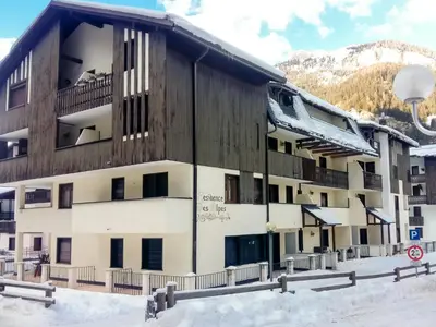 a building in the snow in front of a mountain at Residence Des Alpes in Canazei