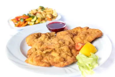a white plate of food with chicken tenders and vegetables at Gasthof Rabenstein in Sarntal