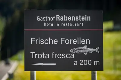 a sign for a hotel and restaurant with a fish on it at Gasthof Rabenstein in Sarntal