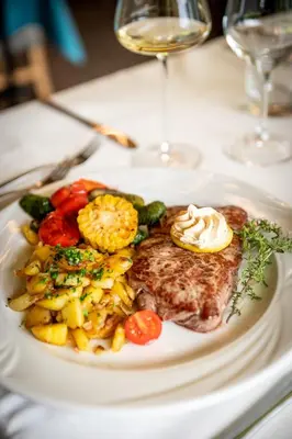a plate of food with meat and vegetables on a table at Gasthof Rabenstein in Sarntal