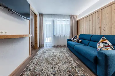 a living room with a blue couch and a tv at Appartamenti Residence Ada in San Cassiano